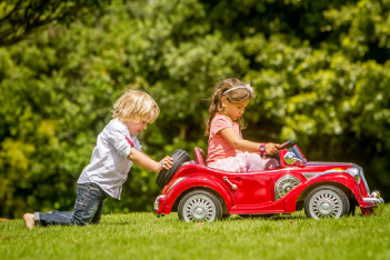 little boy pushing little girl in a toy car