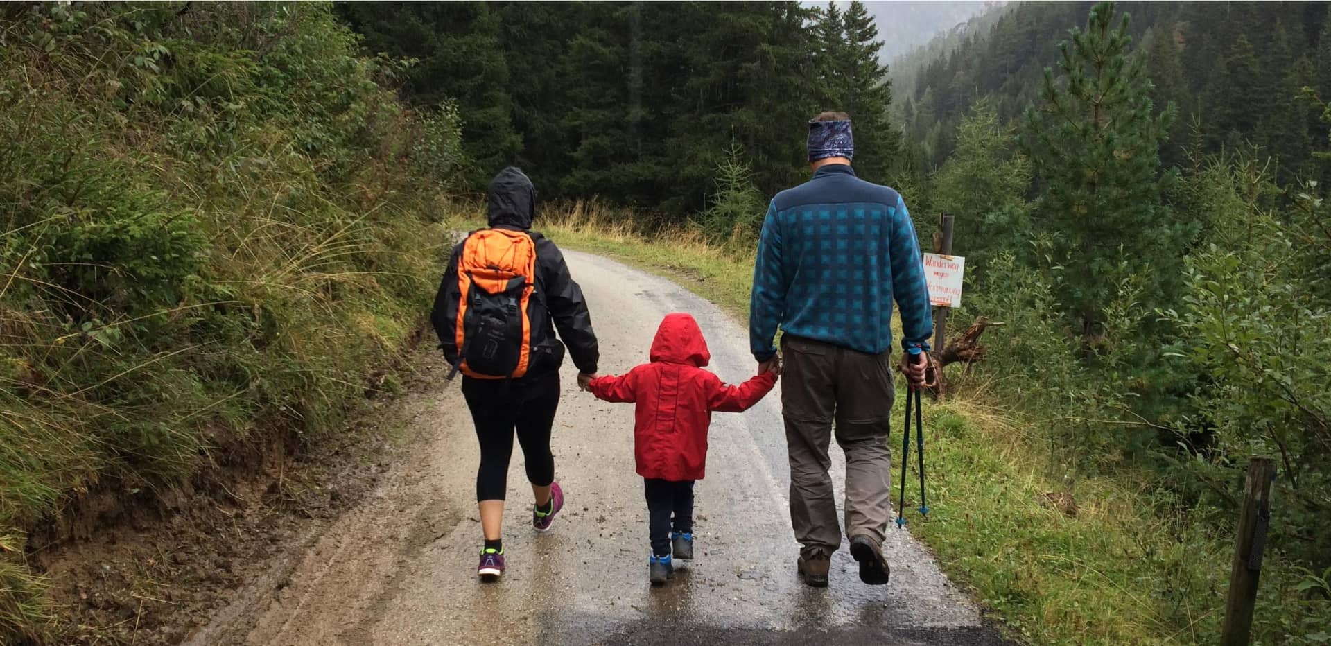 parents and child hiking in the rain